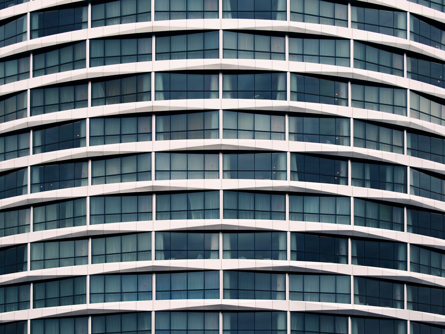Moderne gebouwgevel met donker glas en witte banden.
